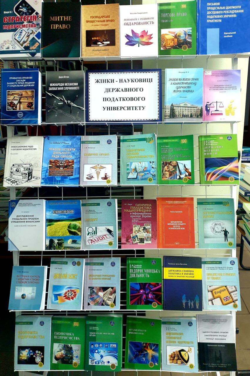 Книжкова виставка у бібліотеці з написом «Жінки-науковиці Державного податкового університету». На полицях представлені наукові видання, підручники та монографії з права, економіки та аудиту