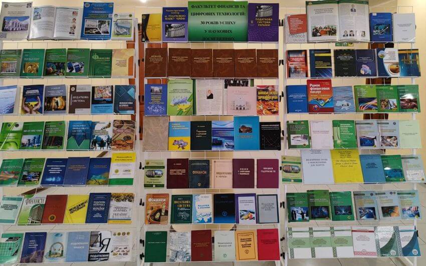 Виставка наукових праць та навчальних посібників на стелажах, присвячена 30-річчю Факультету фінансів та цифрових технологій. На полицях представлено десятки книг, журналів та монографій з питань фінансів, оподаткування та економіки