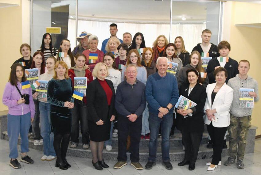 Групове фото студентів та викладачів Державного податкового університету в Ірпені з Джоном Коннорсом. Учасники тримають прапорці України та Ірландії, а також примірники книги про незламність університету