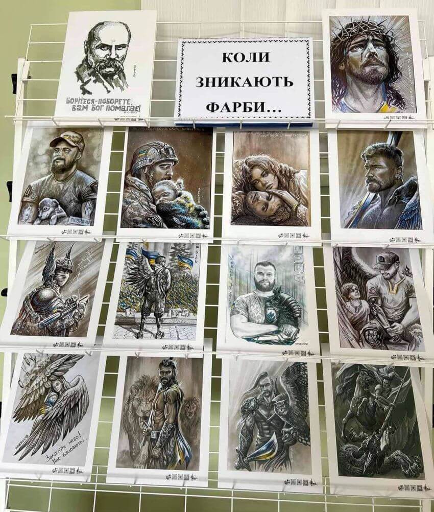 Стенд із патріотичними графічними малюнками, що зображують українських захисників, янголів та біблійні мотиви. Зверху напис: «Коли зникають фарби...»